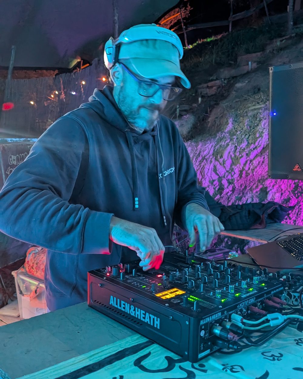DJ Alex Kunjara mixing on an Allen & Heath at a night-time open air floor